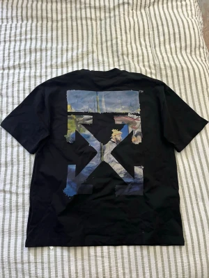Svart Off-White t-shirt med tryck - Snygg svart t-shirt med stort färgglatt grafiskt tryck på ryggen och liten logga framtill. Klassisk passform och korta ärmar, perfekt för en trendig streetwear-look. Jätte kraftigt och skönt material, passar från L-XL