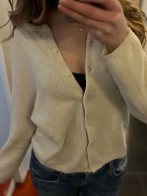 Beige kofta med knappar - Mysig beige kofta med v-ringning och knäppning framtill. Storlek 34. Den är nopprig