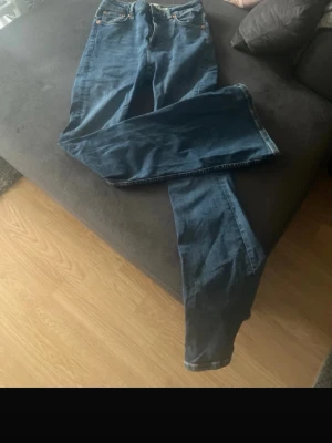 Mörkblå raka jeans från 157 - Säljer ett par mörkblå jeans från 157 med klassisk femficksmodell och raka ben. Jeansen har orangea nitar och detaljer samt dragkedjegylf. Perfekta till en avslappnad och stilren look.