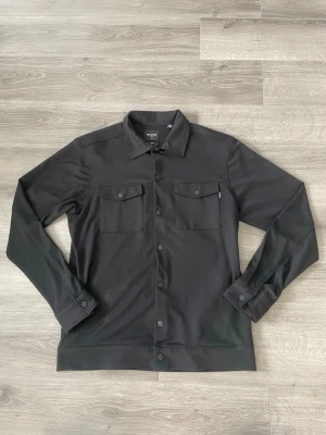 Svart overshirt från Only & Sons - Stilren svart overshirt från Only & Sons med klassisk krage, knäppning framtill och två bröstfickor med lock. Perfekt lager-på-lager-plagg med en clean look. Overshirten är i nyskick och storlek M. Material: Viskos.  Hör av dig!🤙 