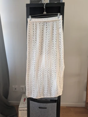 Vit virkad långkjol från Résumé - Superfin vit långkjol från Résumé med virkad design och elastisk midja. Kjolen har ett luftigt och somrigt uttryck, perfekt för att skapa en avslappnad men ändå trendig look. Styla med en enkel topp eller stickad tröja för en snygg outfit.