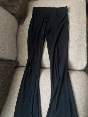 Svarta utsvängda leggings - Svarta leggings med utsvängda ben och hög midja. Mjukt och stretchigt material som sitter skönt på kroppen. Perfekta till en avslappnad stil eller att matcha med en oversized tröja. Som syns är de en liten hål där bak 💞