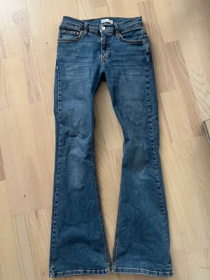 Blå bootcut jeans med låg/mid midja - Säljer ett par klassiska blå bootcut jeans . Jeansen har en snygg tvätt och kontrastsömmar. Perfekta för dig som gillar retrostil och vill ha ett par jeans som sticker ut lite extra.