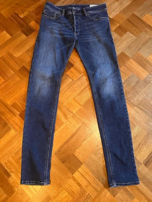 Mörkblå slim jeans från diesel - Snygga mörkblå slim jeans med klassisk femficksdesign och lätt slitna detaljer framtill. Jeansen har normal midja och smala ben, perfekta till en avslappnad stil. Materialet är stretchigt denim för extra komfort. Skriv vid funderingar ! 