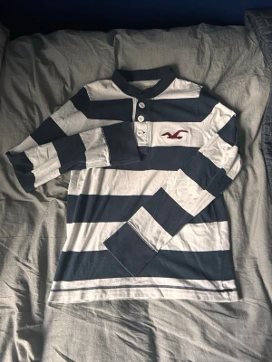 Långärmad Hollister piké - Randig long sleeve polo med en clean 2000s vibe. lätt att styla och väldigt bra passform🔥 Bra skick, inga defekter. Bröstvidd 46 cm längd från krage 60 cm Vid minsta fråga eller fundering är det bara att höra av sig!