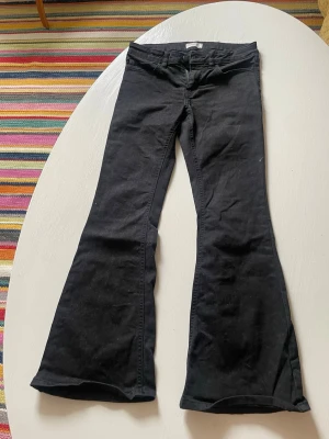 Low waist bootcut jeans - Snygga svarta jeans med utsvängda ben och klassisk femficksmodell. Jeansen har låg midja och stängs med dragkedja och knapp. 