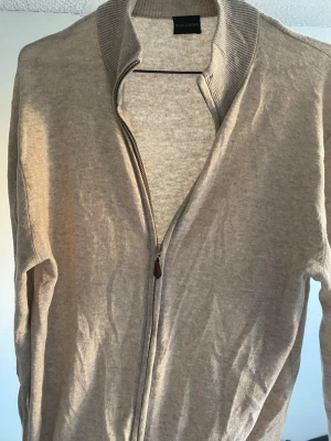 Beige ziptröja från Rose & Born - Snygg beige ziptröja från Rose & Born med ribbad krage och hel dragkedja framtill. Tillverkad i mjukt stickat material som ger en clean och stilren look. Perfekt att slänga på sig över en t-shirt eller skjorta. Riktigt bra skick, enda flawen är på sista bilden! Priset är alltid förhandlingsbart!☺️ 