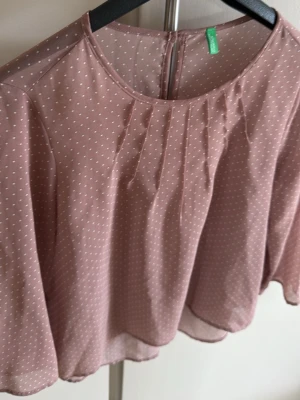 Rosa prickig blus från united colors of benetton - Söt ljusrosa blus med små vita prickar från united colors of benetton Blusen har rund halsringning, lätt transparent tyg och vida trekvartsärmar. Perfekt för en trendig och luftig look. Materialet känns tunt och flowy.
