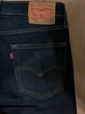 Levi's 502 mörkblå jeans - Klassiska Levi's 502 jeans i mörkblå denim med raka ben och femficksmodell. Snygga kontrastsömmar och ikonisk läderpatch bak i midjan. Perfekta för dig som gillar tidlös stil och kvalitetsjeans.