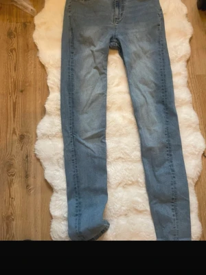 Ljusblå raka jeans  - Säljer ett par ljusblå jeans med klassisk femficksdesign och raka ben. Jeansen har normalhög midja och stängs med dragkedja och knapp. Perfekta till vardags och lätta att matcha med olika stilar.