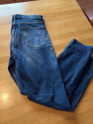 Slim jeans  - Säljer ett par mörkblå jeans med klassisk femficksdesign och raka ben. Jeansen har normal midja och är tillverkade i ett mjukt denimtyg. Passar perfekt till en avslappnad stil och är lätta att matcha med olika plagg.