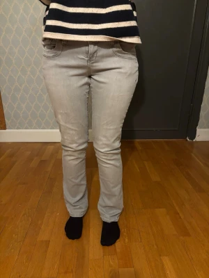 Ljusgrå raka jeans - Säljer ett par ljusgrå jeans med rak passform och klassiska fem fickor. Jeansen har en enkel design utan synliga loggor och är tillverkade i ett mjukt denimtyg. Perfekta för en avslappnad och stilren look.