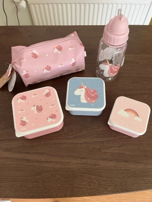 Unicorn set med matlådor och vattenflaska - Säljer ett gulligt set med enhörningstema från Tutek. Setet innehåller tre matlådor i olika storlekar, en vattenflaska med rosa lock och sugrör samt en rosa necessär med enhörningsmotiv. Perfekt för att ta med snacks och dryck till skolan eller utflykten.