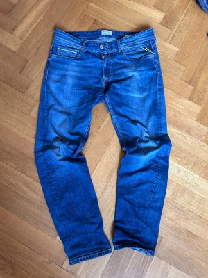  replay Jeans Grover W32 L30 - Säljer ett par klassiska blå jeans från Repaly Jeans med snyggt slitna detaljer och raka ben. Jeansen har fem fickor, knappgylf och coola sömmar på bakfickorna. 