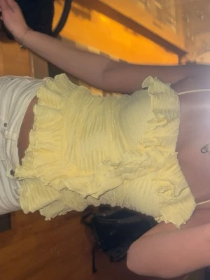 Gul volangig topp - Supersöt ljusgul linnetopp med volanger och smala axelband från BikBok. Aldrig andvänd så den är i nytt skick❣️