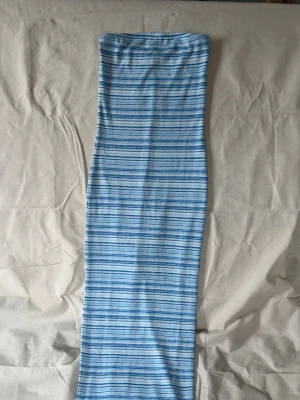 Blåvit randig vad/ankellång tubklänning med slits baktill - Snygg långklänning i blått och vitt med tunna horisontella ränder. Klänningen har en formande passform och en diskret slits baktill för extra rörelsefrihet. Perfekt för dig som gillar en enkel men trendig stil.