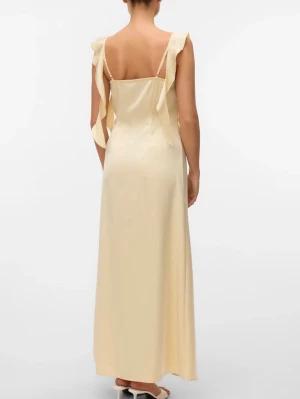 Ljus långklänning i satin med volang - Elegant ljus långklänning i satin med volangdetaljer längs axelbanden och sidorna. Klänningen har raka linjer, smala axelband och en mjuk, skimrande finish som ger en lyxig känsla. Nypris 599kr, helt slutsåld på hemsidan!