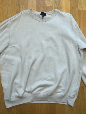 Beige stickad tröja från H&M - En stilren beige stickad tröja från H&M i relaxed fit. Tröjan har rund halsringning, långa ärmar och ribbade muddar vid ärmslut och nederkant. Perfekt för lager-på-lager och enkel att matcha med olika outfits.