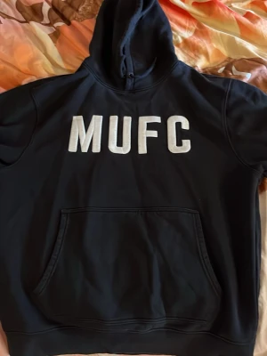     “Official Manchester United hoodie (MUFC) – authentic merch” - En svart Manchester united hoodie i perfekt skick. Använd 2 gånger. Jätte skön insida, varm och mysig. Storlek L. Det finns inga skador på den. Helt perfekt.