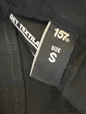 Svarta jeans från 157, storlek S - Säljer ett par svarta jeans från 157 i storlek S. Klassisk femficksmodell, hög midja med dragkedja och knapp framtill. Jeansen har en tight flare passform och är tillverkade i ett mjukt denimtyg som sitter snyggt på kroppen.