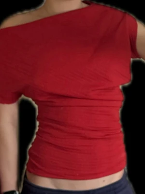 Röd oneshoulder topp - Trendig röd topp med oneshoulder-design och tight passform. Toppen har kort ärm vilket ger en cool look. Perfekt att styla med jeans eller kjol för en snygg outfit.