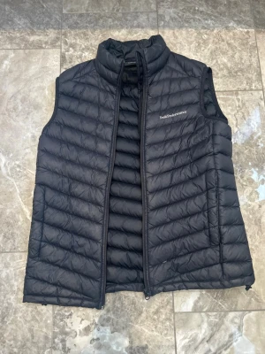 Peak Performance väst  - Snygg svart dunväst från Peak Performance. Perfekt till våren. Storlek medium 