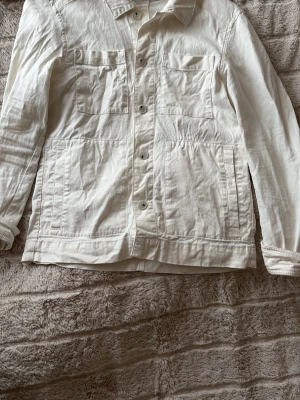 Vit overshirt från J.Lindeberg XS - Snygg vit overshirt från J.Lindeberg i storlek XS sitter som S . Klassisk modell med två bröstfickor och två sidofickor, knäppning framtill och krage. Perfekt att slänga över en hoodie eller t-shirt för en clean och stilren look.