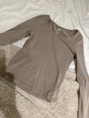 Beige långärmad topp från lager 157 - En basic beige långärmad topp från lager 157 med rund halsringning. Tillverkad i mjuk bomull, perfekt att styla med jeans eller kjol. Enkel och stilren design som funkar till många olika looks.