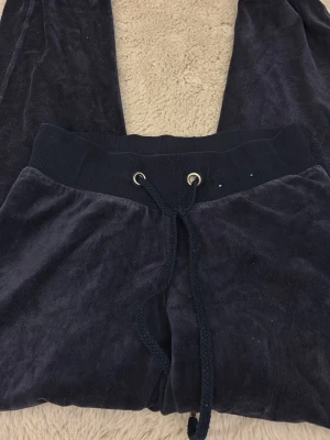 Mörkblå velour mjukisbyxor XS - Mysiga mörkblå mjukisbyxor i velour med bred resår och dragsko i midjan. Perfekta för chill dagar och har en klassisk, avslappnad passform. Byxorna har ribbade muddar och är supermjuka mot huden.