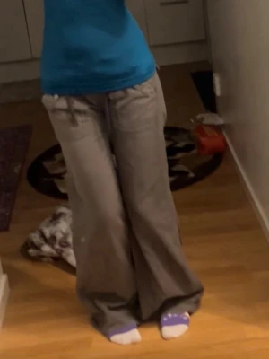 Gray Brown Cargo pants - Säljer ett par gråa bruna cargo byxor med breda ben och stora fickor både fram och bak men sitter lite tightare på låren, vällldigt low wasit och ger big but. Siter bra för mig  som e 171cm. Jag tänkte ha dem i sommaren men behöver pengar nu. Jag syde lite mer low wasit på dem men de går sprätta up. Jag har faktiskt ingen aning var den e från de ser vintage ut, jag fick den av en snäll vän.