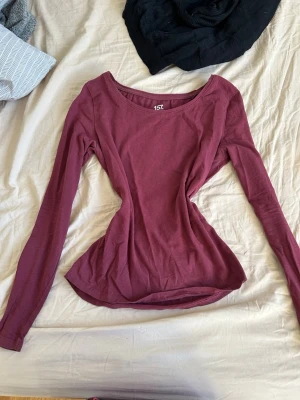 Vinröd långärmad topp från 157 - Säljer en vinröd långärmad topp från 157. Toppen har rund halsringning och är tillverkad i mjuk bomull med lite stretch för en bekväm passform. Perfekt att styla med jeans eller kjol för en enkel och snygg look.