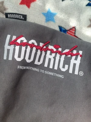 Gråa baggy mjukisbyxor från Hoodrich  - Snygga gråa mjukisbyxor från Hoodrich med broderad och tryckt logga framtill. Byxorna har resår i midjan och mudd vid benslut för en skön passform. Perfekta för chill eller streetwear-stil. Passar för S och XL (13-15)