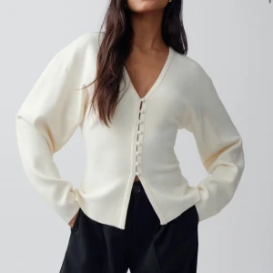 shaped knitted cardigan - Stilren krämvit kofta med v-ringning och dekorativa klädda knappar framtill. Koftan har en avslappnad passform, långa ärmar och är tillverkad i ett mjukt stickat material. Perfekt för lager på lager och enkel att matcha med olika outfits.