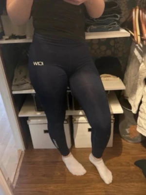 träningstights från ICIW - Säljer ett par marinblå träningstights från ICANIWILL med logga på höften och vaden. Tightsen har hög midja och scrunch i rumpan som former kroppn. Perfekta för gymmet eller löprundan. (Bud välkomnas)
