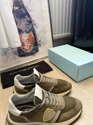 Gröna Philippe Model sneakers - Snygga sneakers från Philippe Model i olika nyanser av grönt med detaljer i beige och vitt. Skorna har en klassisk låg siluett, paneler i mocka och mesh samt en kontrasterande logga på sidan. Perfekta för dig som gillar stilrena och trendiga sneakers.