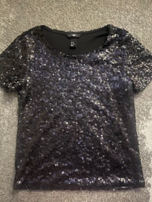 Svart paljettopp från H&M - Glittrig svart topp från H&M täckt med paljetter. Storlek xs💞💞