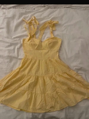 Kort klänning med knytband - Söt klänning med volang och knytband på axlarna. Klänningen har en figurnära överdel och 