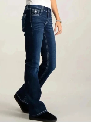 Mörkblå lågmidjade jeans från gina young - Snygga mörkblå bootcut jeans från gina tricot med kontrasterande vita sömmar och dekorativa fickor bak. Jeansen har låg midja och klassisk femficksdesign. Perfekta för dig som gillar en avslappnad men trendig stil. (Felsydda på vänster ben, sista bilden)