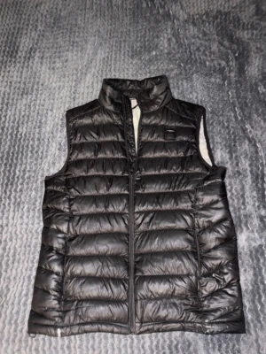 Lindbergh Väst - Snygg svart Lindbergh Väst i storlek S skick enligt bilder. Höger fickas dragkedja funkar ej