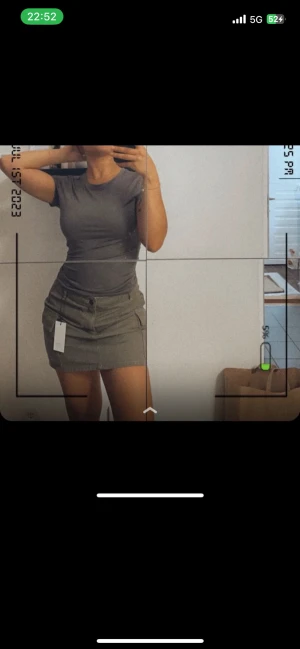 Grön cargokjol med fickor - Säljer en snygg grön cargokjol från Pigalle. Kjolen är kort, har två stora sidofickor och stängs med dragkedja och knapp framtill. Perfekt till en enkel topp eller hoodie för en chill look.