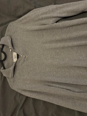 Grå halvzip-tröja från Produkt - Snygg grå långärmad tröja från Produkt med halv dragkedja och ståkrage. Perfekt för lager-på-lager och enkel att matcha med jeans eller chinos. Mjuk bomullskänsla och stilren design som funkar året runt. Skicka gärna bud.