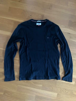 Svart långärmad tröja Tommy Hilfiger - Snygg svart långärmad tröja från Tommy Hilfiger Denim med rund halsringning och liten logga på bröstet. Tillverkad i mjukt material som känns skönt mot huden. Perfekt basplagg för en clean och stilren look.