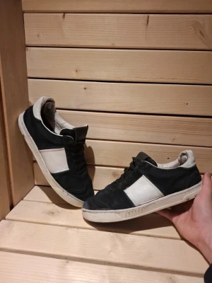 Svart vita Valentino Flycrews med mockadetalj - Snygga Valentino Flycrews i svart och vitt. Skorna är i mocka med vita paneler på sidorna och svarta snören. Skorna har en liten defekt i fram vilket ses lite otydligt på bilderna bara att fråga om ni vill ha fler bilder på det, de saknas även några spikar på båda skorna skriv om ni vill ha mer bilder på de eller om ni vill diskutera priset. De är i storlek 39 men de funkar för mig som har 42 om jag tar ur sulan så de är väldigt stora i storlek med sula skulle jag säga att de är runt 40-41