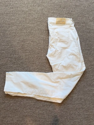 Vita jeans från Jacob Cohën - Snygga vita jeans från Jacob Cohën med klassisk femficksmodell och raka ben. Byxorna har en diskret logga på bakfickan och patch i läder bak i midjan. Tillverkade i mjukt bomullstyg med stretch för extra komfort. Väldigt tunna jeans. Priset kan diskuteras!!!