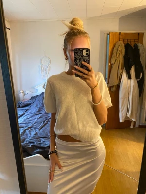 Vit tight kortkjol i bomull - Säljer en vit tight kortkjol i mjukt bomullsmaterial. Kjolen har en enkel och stilren design med hög midja och slät yta utan synliga detaljer. Perfekt för dig som gillar minimalistisk och clean stil.
