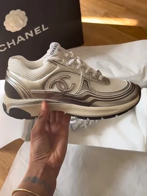 Chanel silver sneakers  - Använt 2 gånger. Helt nya. Snygga vita sneakers från Chanel med ikonisk CC-logga på sidan. Skorna har mesh och läderdetaljer, vita snören och svarta samt beige inslag i sulan. Perfekta för dig som vill ha en lyxig och trendig look med exklusiv känsla.  Storlek 35 men passar även 36
