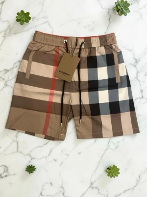 Rutig shorts från Burberry med snörning - Säljer ett par klassiska rutig shorts från Burberry i beige, brunt och rött. Shortsen har snörning i midjan och är tillverkade i mjuk bomull med elastan för extra komfort. Perfekta för dig som vill ha en stilren och tidlös look.