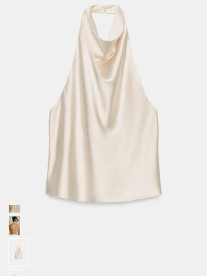 Champagnefärgad/vit halterneck linnetopp - Snygg champagnefärgad halterneck topp i glansigt satinliknande material. Toppen har en draperad framsida och öppen rygg med knäppning i nacken. Perfekt för dig som vill ha en stilren och trendig look. Den är också mot vit hållet färg mässigt om man ser den i verkligheten.