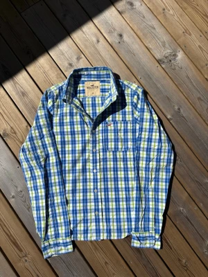 Hollister skjorta ~ Vintage  - Säljer denna skjorta från Hollister. Storlek M. Passar perfekt för dig som är mellan 175-180! Hör av er vid frågor eller minsta fundering 🙌  Märke: Hollister  Storlek: M  Färg: Ljusgrön, blå och vit/rutig  Skick: Mycket bra utan defekter   Se mått nedan:  Längd: 66,5 cm  Bred: 48,5 cm  Ärm: 67 cm