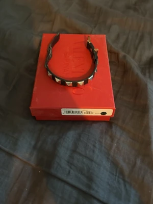Valentino svart läderarmband - Snyggt svart armband från Valentino i äkta läder med ikoniska pyramidformade nitar i silverfärg. Justerbart spänne för perfekt passform. Kommer i original röd box med etikett. Perfekt accessoar för en edgy och trendig stil.    Box finns med allt är äkta men använt 😀